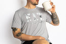 Man wearing the Rest Day PJ F.I.T. grey pyjama t-shirt and shorts set, relaxing with a coffee mug