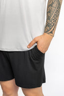 Man wearing the Rest Day PJ F.I.T. grey pyjama t-shirt and shorts set, side view with hands in pockets